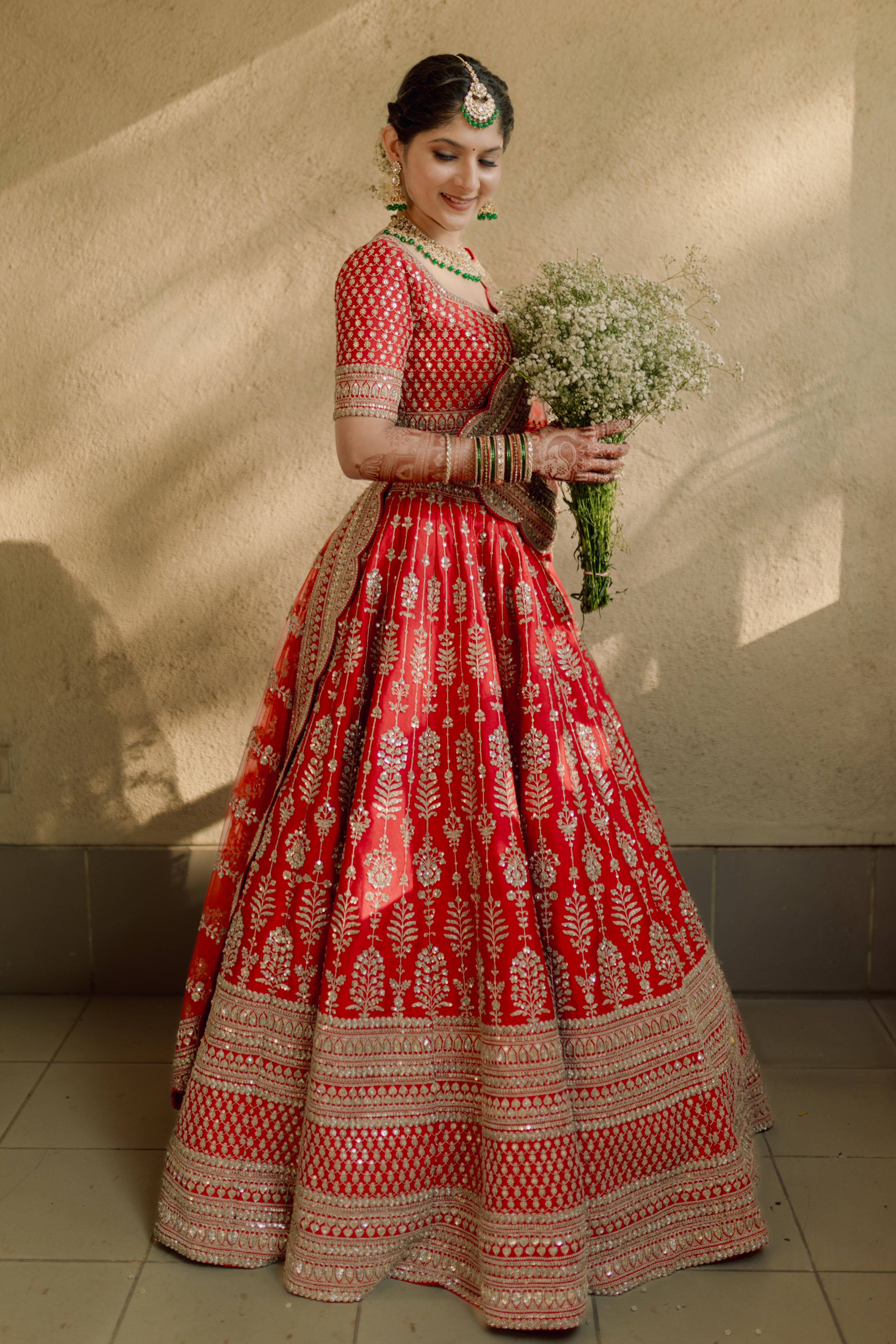 Red bridal lehenga with bouquet — full length
